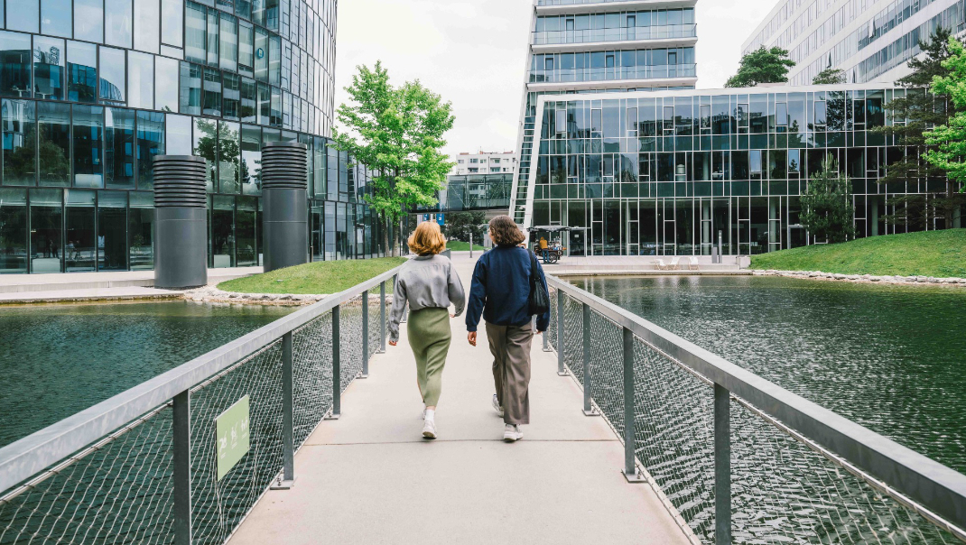 Zwei Frauen auf Brücke vor moderner Architektur