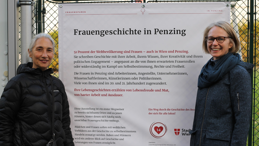 Zwei Frauen vor Plakat zur Frauengeschichte Benzin